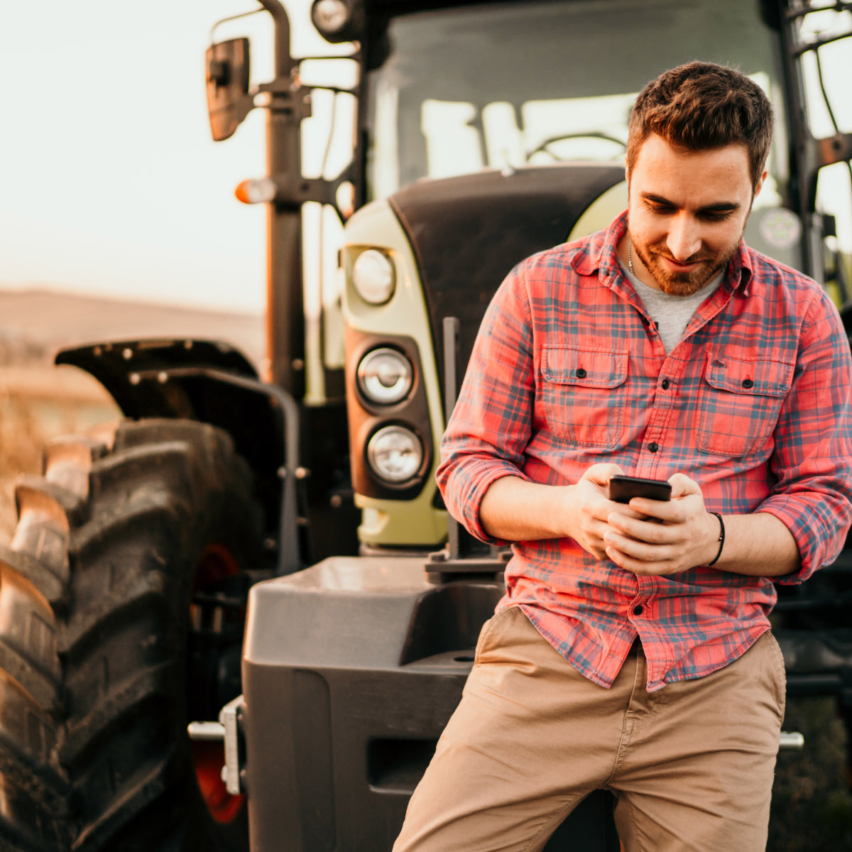 Man receiving a mobile notification from his cellular sensor while riding tractor in field